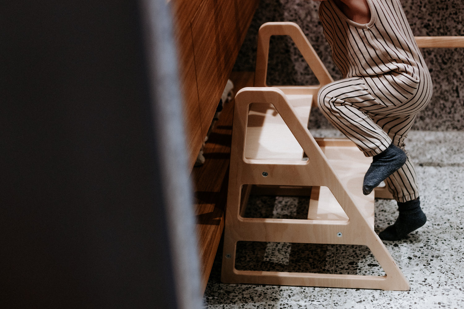 Kind steigt selbstständig auf den Tritthocker Step